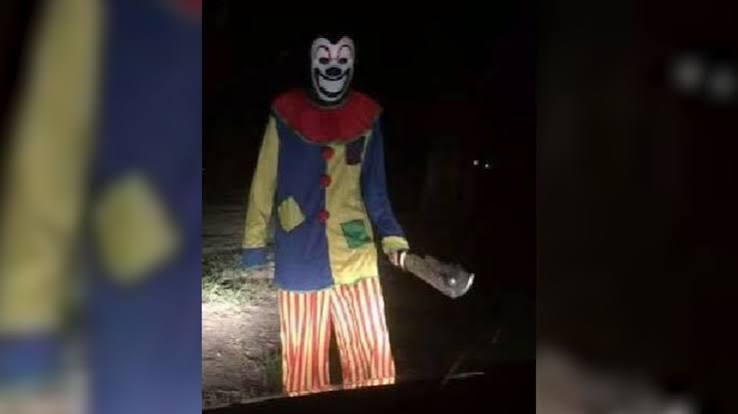Clown standing at night holding a bag